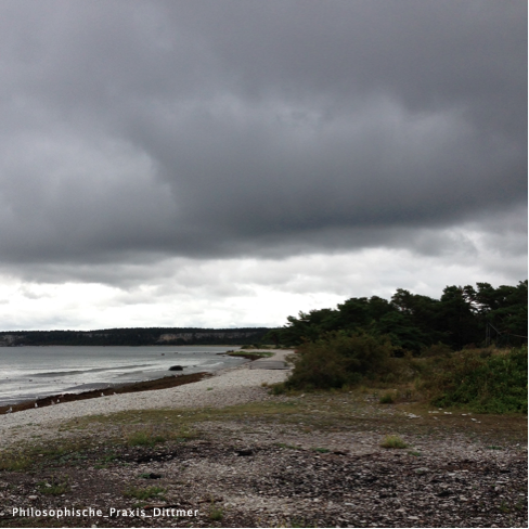 Aufziehende dunkle Wolken über einer Bucht als Symbol für Unerschütterlichkeit
